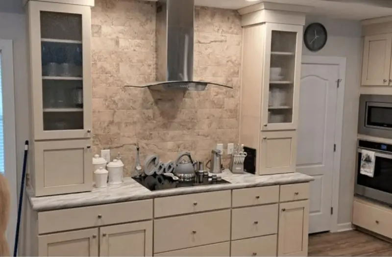Kitchen with cream cabinets, glass-front uppers and a stainless range hood