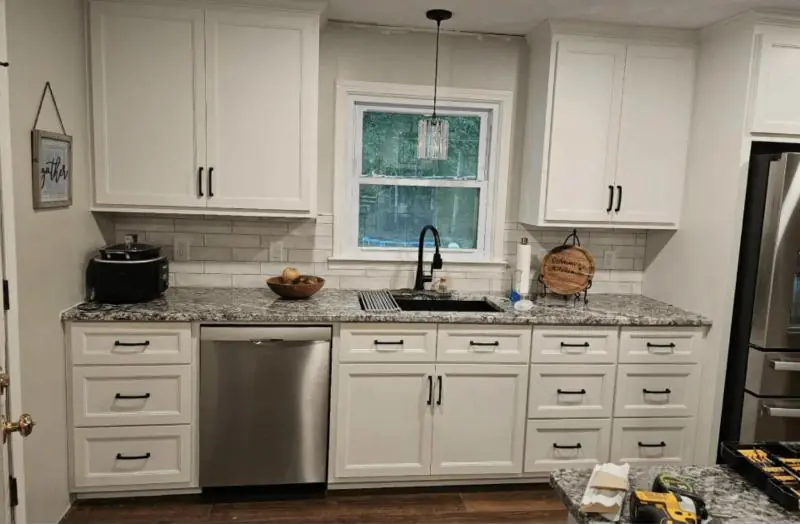 Kitchen with white shaker cabinets, subway tile backsplash and granite counters